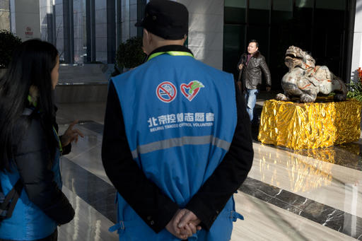 In this Friday, Dec. 2, 2016 photo, anti-smoking volunteers, in blue, prepare to inspect an office building for offenders in Beijing. As China considers a nationwide ban on smoking indoors, the fight is well underway in Beijing, which banned smoking in restaurants and other public places 18 months ago. Zealous volunteers and anti-smoking advocates have made some headway against millions of occasionally intransigent smokers and the state-run cigarette monopoly, a large and powerful force in China's government and economy. (AP Photo/Ng Han Guan)