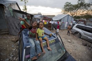 In this Dec. 5, 2016 photo, children sit on a parked car in the Delmas tent camp set up nearly seven years ago for people displaced by the 2010 earthquake, in Port-au-Prince, Haiti. The number of people in these makeshift communities has declined since the immediate aftermath, but those who remain are a stubborn reminder that this impoverished country has yet to fully recover from one of the worst natural disasters in history. AP