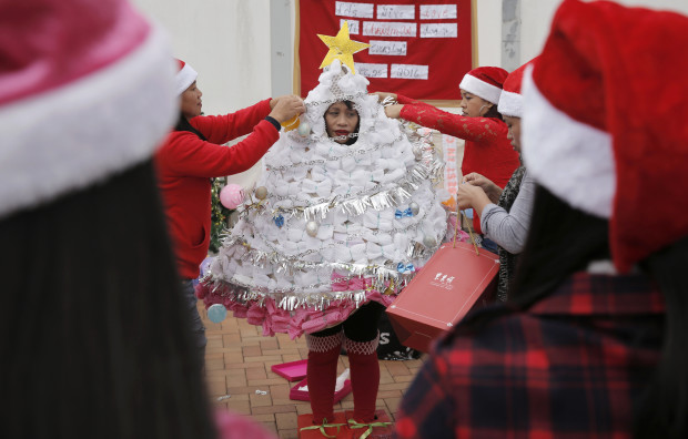 A Filipino domestic helper is helped by her friends to dress up as a Christmas tree made with recycled materials and leaves as they hold a costume contest to celebrate the festival season in Hong Kong, Sunday, Dec. 25, 2016. (AP Photo/Kin Cheung)