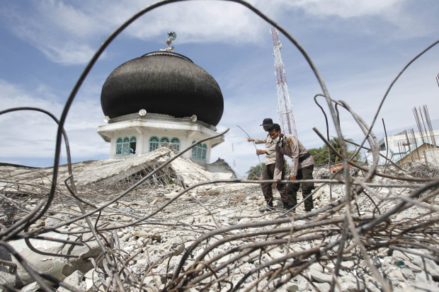 Police officers help clear rubble at the ruin of a mosque collapsed in Wednesday's earthquake in Tringgading, Aceh province, Indonesia, Saturday, Dec. 10, 2016. Tens of thousands people have been displaced by the powerful earthquake that hit Indonesia's Aceh province, authorities said Saturday, as the government and aid agencies pooled efforts to meet the basic survival needs of shaken communities. (AP Photo/Trisnadi)