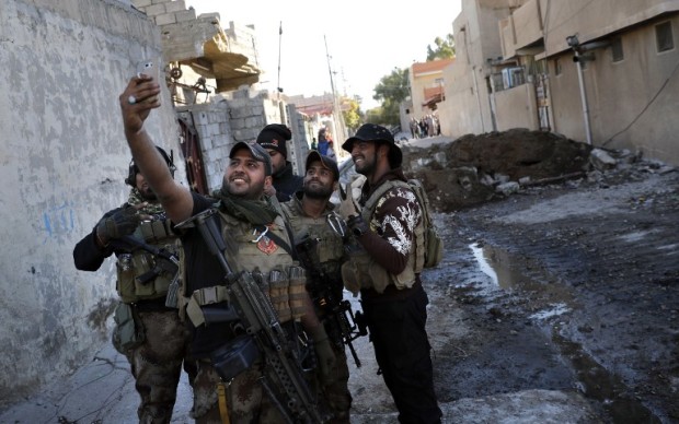 A soldier from the Iraqi Special Forces takes a selfie on a street in the Aden district of Mosul after troops almost entirely retook the area from Islamic State (IS) group jihadists on November 22, 2016. The fighting inside the city so far has focused on eastern neighbourhoods, which elite counter-terrorism and army forces entered earlier this month. The Islamic State group has offered fierce resistance to defend its last remaining bastion in Iraq, the city where its leader Abu Bakr al-Baghdadi proclaimed a caliphate in June 2014. / AFP PHOTO / THOMAS COEX