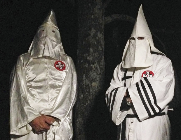In this Friday, Dec. 2, 2016 photo, two masked Ku Klux Klansmen stand on a muddy dirt road during an interview near Pelham, N.C. The KKK and other white extremist groups don't like being called "white supremacists," a phrase that dates to the earliest days of white racist movements in the United States. (AP Photo/Jay Reeves)