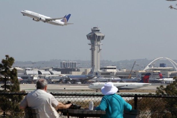 LOS ANGELES, CA - APRIL 22: People watch as a United Airlines jet passes the air traffic control tower at Los Angles International Airport (LAX) during take-off on April 22, 2013 in Los Angeles, California. Delays have been reported throughout the nation because of the furloughing of air traffic controllers under sequestration. The average delay overnight in the Southern California Terminal Radius Approach Control (TRACON) was was three hours.   David McNew/Getty Images/AFP