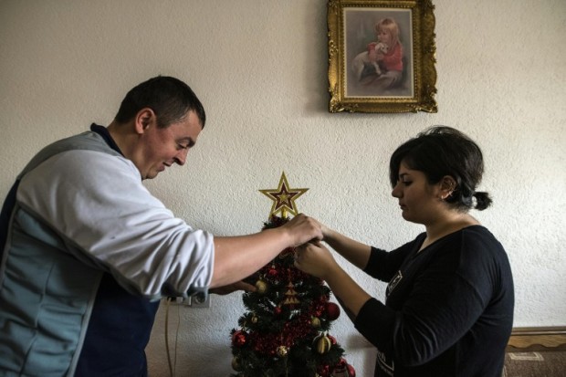 TO GO WITH AFP STORY BY JASMINA MIRONSKI AND RACHEL O'BRIEN Noora Arkavazi (R) and her husband Bobi Dodevski decorate a Christmas tree in their home in Kumanovo on December 21, 2016. The scene was hardly conducive to romance: she was a sick Iraqi in a wave of refugees trying to enter Serbia, while he belonged to the stern Macedonian police force keeping guard. But Noora Arkavazi, a Kurdish Muslim, and Orthodox Christian Bobi Dodevski quickly fell in love after they met at the muddy border in early March -- and celebrated their wedding four months later.   / AFP PHOTO / Robert ATANASOVSKI