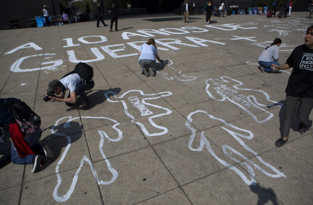People paint outlines of bodies as part of a memorial for those killed, on the 10th anniversary of the drug war's start, at the Monument  for the the Mexican Revolution, in Mexico City, Sunday, Dec. 11, 2016. Ten years after Mexico declared a war on drugs, the offensive has left some major drug cartels splintered and many old-line kingpins like Joaquin "El Chapo" Guzman in jail, but done little to reduce crime or violence in the nation's roughest regions.(AP Photo/Rebecca Blackwell)