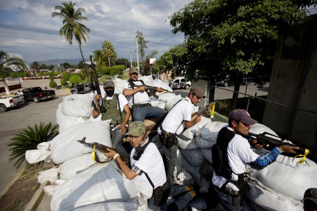 FILE - In this Jan. 12, 2014 file photo, men belonging to the Self-Defense Council of Michoacan, ride on a sandbag-filled truck while trying to flush out alleged members of The Caballeros Templarios drug cartel from the town of Nueva Italia, Mexico. The Caballeros Templarios exerted near-total control of the lives of Michoacan residents, telling them when to pick limes or avocados, and determining what price they would get paid. While they largely chased the Templarios out, other new gangs have taken root, though without the total, brazen control of the old cartels. (AP Photo/Eduardo Verdugo, File)