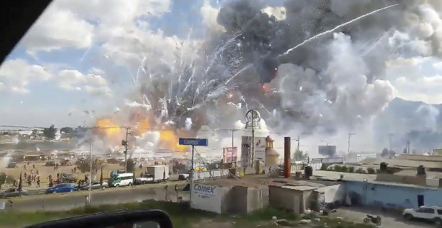 This image made from video recorded from a passing car shows an explosion ripping through the San Pablito fireworks' market in Tultepec, Mexico, Tuesday, Dec. 20, 2016. Sirens wailed and a heavy scent of gunpowder lingered in the air after the afternoon blast at the market, where most of the fireworks stalls were completely leveled. According to the Mexico state prosecutor there are at least 26 dead. (Jose Luis Tolentino via AP)