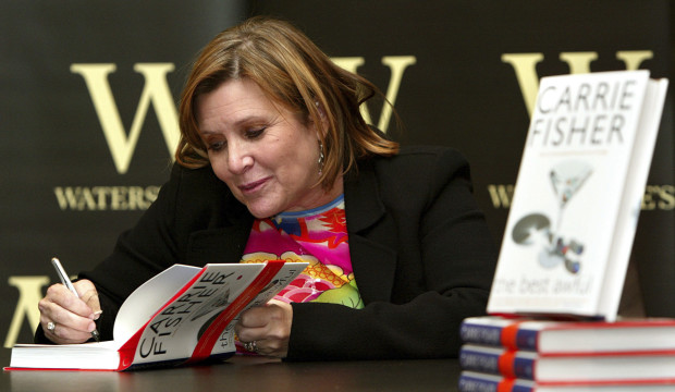 In this Friday, Feb. 20, 2004 file photo, author Carrie Fisher autographs her new book "The Best Awful" at a promotional event in London. On Tuesday, Dec. 27, 2016, a publicist said Fisher has died at the age of 60. AP