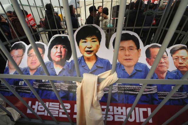 Portraits of South Korea's President Park Geun-Hye (C) and her aides are set in a mock prison during a rally against the scandal-hit president in central Seoul on December 17, 2016. Tens of thousands of protesters turned out in Seoul for the eighth straight week on December 17, pushing for the swift and permanent removal of impeached South Korean President Park Geun-Hye. / AFP PHOTO / JUNG Yeon-Je