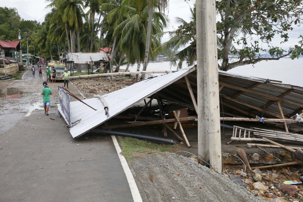 The entire roof of a store partially blocks the road after being swept by typhoon Nock-Ten, at Mabini township, Batangas province south of Manila, Philippines a day after Christmas Day on Monday, Dec. 26, 2016. The powerful typhoon slammed into the eastern Philippines on Christmas Day, spoiling the biggest holiday in Asia's largest Catholic nation but weakened slightly on Monday as it roared toward a congested region near the country's capital, officials said. They said that Typhoon Nock-Ten cut power to five provinces as well as displacing thousands of villagers and travelers in Asia's Catholic bastion.(AP Photo/Bullit Marquez)