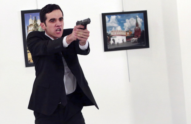 ADDS THE NAME OF THE GUNMAN - A man identified as Mevlut Mert Altintas holds up a gun after shooting Andrei Karlov, the Russian Ambassador to Turkey, at a photo gallery in Ankara, Turkey, Monday, Dec. 19, 2016. Shouting "Don't forget Aleppo! Don't forget Syria!" Altintas fatally shot Karlov in front of stunned onlookers at a photo exhibit. Police killed the assailant after a shootout. (AP Photo/Burhan Ozbilici)