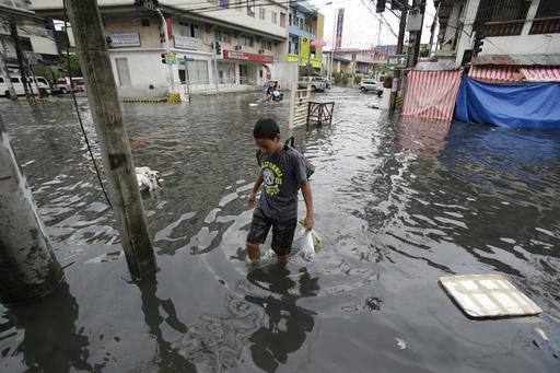 A man wades along a flooded street caused by rains from Typhoon Nock-Ten in Quezon city, north of Manila, Philippines on Monday, Dec. 26, 2016. The powerful typhoon slammed into the eastern Philippines on Christmas Day, spoiling the biggest holiday in Asia's largest Catholic nation, where a governor offered roast pig to entice villagers to abandon family celebrations for emergency shelters. (AP Photo/Aaron Favila)