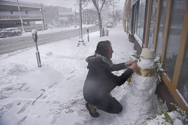 Cassie Maurer, with QT Cakes, puts the finishing touches on a snow man in front of the shop during a snow storm, Friday, Nov. 18, 2016, in Sioux Falls, S.D.   The National Weather Service has issued a blizzard warning for Friday in eastern parts of North and South Dakota and Minnesota, as well as winter storm warnings for other parts of those states and Nebraska. (Joe Ahlquist/The Argus Leader via AP)