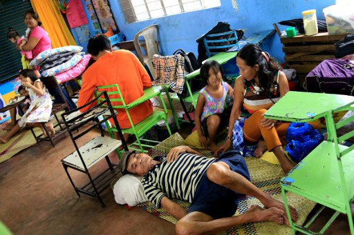 Residents sit inside a classroom at the Central Elementary School which was turned into an evacuation centre in Santo Domingo, Albay province on December 25, 2016 due to approaching Typhoon Nock-Ten. Thousands of residents were fleeing coastal and other hazardous areas in the eastern Philippines on December 25 as a powerful typhoon barrelled towards the disaster-prone archipelago.  AFP PHOTO 
