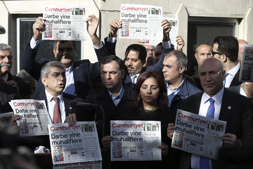 FILE - In this Oct. 31, 2016, file photo, Journalists and lawmakers hold a latest copy of Cumhuriyet newspaper outside its Istanbul headquarters after police detained chief editor Murat Sabuncu and two columnists of Turkey's opposition Cumhuriyet newspaper and had warrants to detain 10 other senior staff members, in Istanbul, Turkey. In a two-month period, Turkish President Recep Tayyip Erdogan's government detained more than 100 journalists and closed down at least 100 news outlets, a report by the Committee to Protect Journalists, said on Tuesday, Dec. 12. (AP Photo/Emrah Gurel, File)