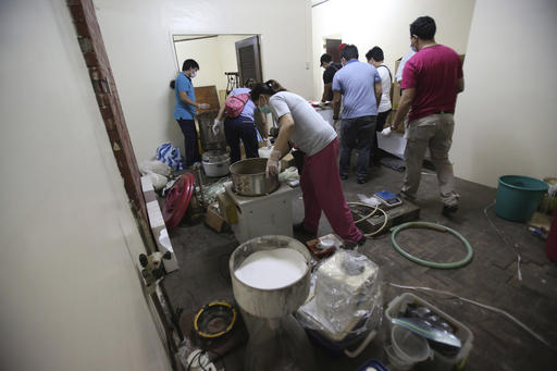 Members of the National Bureau of Investigation inspect laboratory materials used to manufacture Methamphetamine, locally known as Shabu, inside a house in San Juan, east of Manila, Philippines on Friday, Dec. 23, 2016. Philippine authorities say they have arrested six people in what could be one of the largest drug seizures under President Rodrigo Duterte. (AP Photo/Aaron Favila)