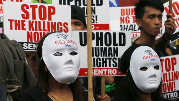 Masked protesters display placards as they gather for a rally near the Presidential Palace to mark International Human Rights Day, Saturday, Dec. 10, 2016 in Manila, Philippines. The protesters are calling on the Government for an end to extra-judicial killings in the country which already claimed the lives of more than 4,000 people. (AP Photo/Bullit Marquez)