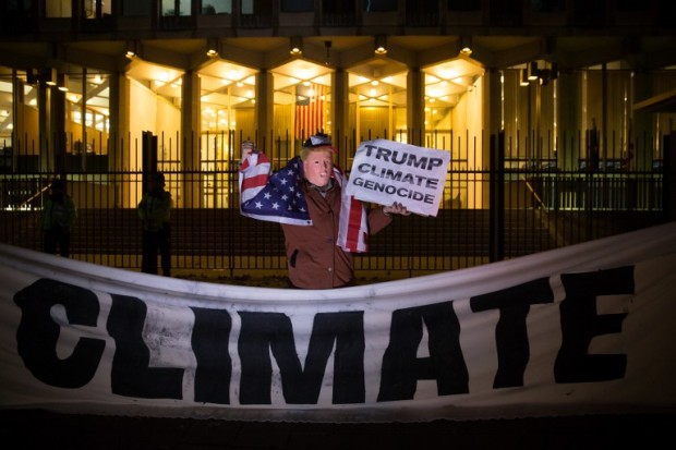 A man wearing a mask portraying newly elected US president-elect Donald Trump poses with a sign during a demonstration against Trump's vow to withdraw the US from the Paris Climate Accord outside the US Embassy in central London in November 18, 2016.  A UN climate conference on November 18 appealed to the "pragmatism" of president-elect Donald Trump, who has threatened to pull the US out of a global pact to rein in global warming. The first gathering of the UN's climate forum since last year's adoption of the Paris Agreement to curtail disastrous global warming, is tasked with drafting a roadmap for its execution. It has been overshadowed by uncertainty about Trump's vow to "cancel" the pact to rein in greenhouse gas emissions blamed for planet warming.  / AFP PHOTO / Daniel LEAL-OLIVAS