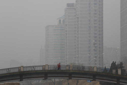 Chinese men wearing masks to filter the pollution walk on a bridge near building shrouded by fog and pollution in Beijing, Thursday, Jan. 5, 2017. China has long faced some of the worst air pollution in the world, blamed on its reliance of coal for energy and factory production, as well as a surplus of older, less efficient cars on its roads. Inadequate controls on industry and lax enforcement of standards have worsened the pollution problem. (AP Photo/Andy Wong)