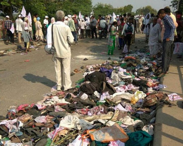 Indian bystanders gather near discarded belongings at the roadside following a fatal stampede in Varanasi on October 15, 2016.                    A stampede at a religious gathering in northern India killed at least 19 people October 15 as thousands of devotees of a controversial guru tried to cross a bridge at once, police said. The followers of Jai Gurudev, a leader of a local religious sect, had gathered on the outskirts of Varanasi, a Hindu holy town on the banks of river Ganges in Uttar Pradesh state, when the deadly stampede broke out.  / AFP PHOTO / STR