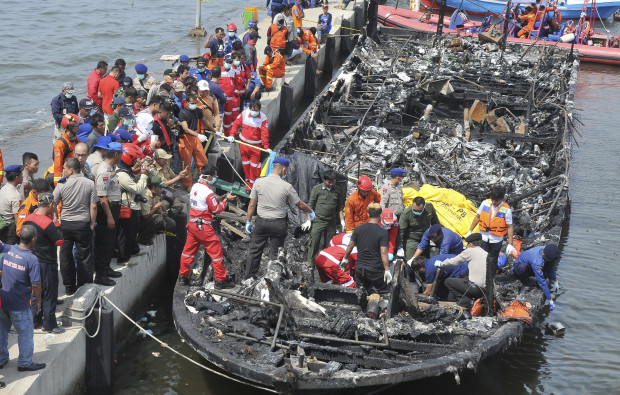 Rescuers search for victims from the wreckage of a ferry that caught fire off the coast of Jakarta after it was docked at Muara Angke Port in Jakarta, Indonesia, Sunday,  Jan. 1, 2017. The vessel was carrying more than 230 people from the port to Tidung, a resort island in the Kepulauan Seribu chain, when it caught fire, officials said. (AP Photo/Rhana Ananda)