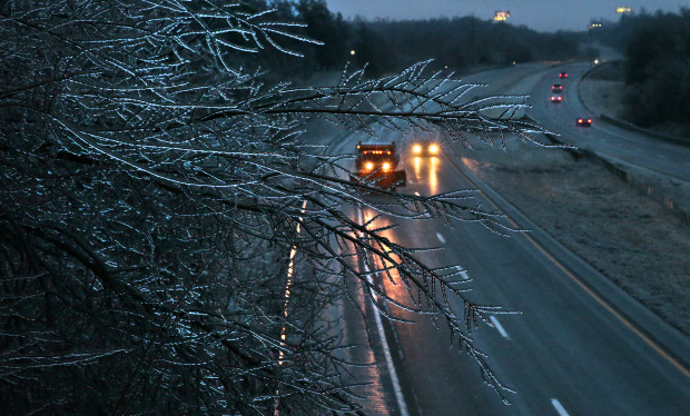 A Missouri Department of Transportation salt truck spreads ice melt on Interstate 55 as coated tree branches sway overhead as seen from the Main Street bridge on Friday, Jan. 13, 2017 in Festus, Mo.  A thick glaze of ice covered roads from Oklahoma to southern Illinois on Friday amid a winter storm that caused numerous wrecks, forced school cancellations, grounded flights and prompted dire warnings for people to stay home. (Robert Cohen/St. Louis Post-Dispatch via AP)