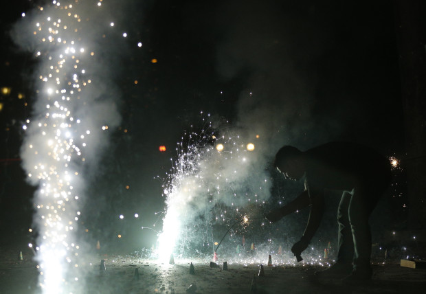 An Indian man lights firecrackers on the street during the New Year celebration in Mumbai, India, Sunday, Jan. 1, 2017. (AP Photo/Rafiq Maqbool)