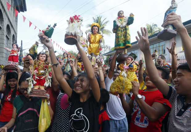 Roman Catholic devotees raise their images of the Child Jesus to be blessed with holy water following a mass to celebrate its feast day Sunday, Jan. 15, 2017 in Manila, Philippines. Thousands of images of The Child Jesus are paraded around the streets in the annual celebration in this only predominantly Catholic nation in Asia. (AP Photo/Bullit Marquez)