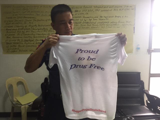 A police officer of the Manila Police District's Ermita station shows off the white t-shirt to be worn by rehabilitated drug users during the Black Nazarene procession on Jan. 9, 2017. (PHOTO BY AIE BALAGTAS SEE / INQUIRER)