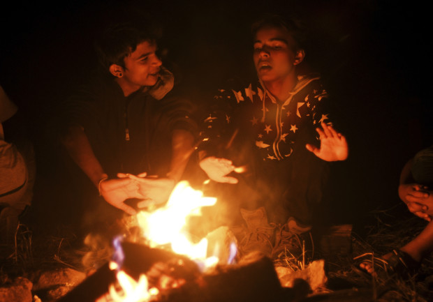 In this Sept. 10, 2016, photo, Bhim Adhikari, 16, left, and Madhav Khadka, 15, both Nepalese refugees, warm themselves around a campfire in Evergreen, Colo. The two are part of Boy Scout Troop 1532, which is made up almost entirely of refugees. The troop's leaders say it allows the scouts to be themselves, even as the outside world seems stacked against refugees. (AP Photo/Thomas Peipert)