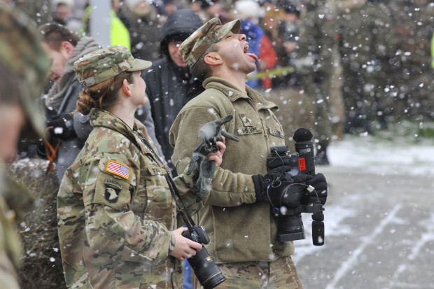 A U.S. Army soldier plays with falling snow during the official welcoming ceremony of the U.S. troops in Zagan, Poland, Saturday, Jan. 14, 2017. The ceremony comes 23 years after the last Soviet troops left Poland and also marks a new historic moment — the first time any Western forces are being deployed on a continuous basis to NATO's eastern flank. (AP Photo/Krzysztof Zatycki)