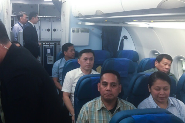 BACK TO MANILA. Photo captured with a mobile phone show President Rodrigo R. Duterte sitting at the second to the last row of the economy class portion of a commercial airline as he flies back to the nation's capital on January 5, 2017 after spending his New Year break in Davao City. Also in the photo is Special Assistant to the President Christopher 'Bong' Go. Presidential Photo