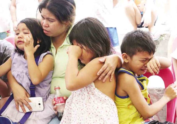 Marilyn Villanueva comforts her grieving children aged 9, 8 and 6. She told the Inquirer in a previous interview that Emilyn, the eldest of her four children, was the one who looked after her siblings whenever she and her husband were out. —Joan Bondoc