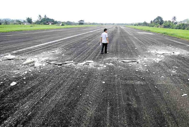 An airport official inspects the damage to the runway that forced the closure of the Surigao airport. —AFP