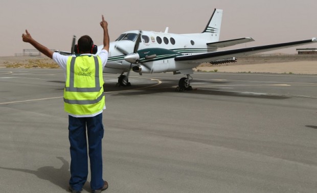 TO GO WITH STORY BY ALI KHALIL  An airport employee signals to a twin-propeller Beechcraft plane that is fixed with salt flares which are fired into a promising cloud to increase condensation and hopefully trigger rainfall, as it prepares to take off on a cloud-seeding mission at al-Ain airport on April 23, 2015.  Being one of the most arid countries in the world, the United Arab Emirates is striving to capture every droplet by inducing clouds to produce rain and meet its ever-increasing water needs. AFP PHOTO / MARWAN NAAMANI / AFP PHOTO / MARWAN NAAMANI