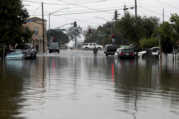 A man walks through floodwaters Monday, Feb. 20, 2017, in Salinas, Calif. Forecasters issued flash flood warnings Monday throughout the San Francisco Bay Area and elsewhere in Northern California as downpours swelled creeks and rivers in the already soggy region. (Nic Coury/Monterey County Weekly via AP)