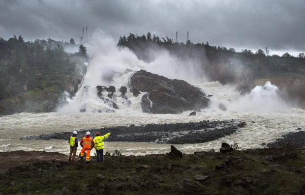 A member of Cal Fire, right, talks to workers on the Oroville Dam project in front of the main spillway in Oroville, Calif., Monday, Feb. 20, 2017. Forecasters issued flash flood warnings Monday throughout the San Francisco Bay Area and elsewhere in Northern California as downpours swelled creeks and rivers in the already soggy region. (Hector Amezcua/The Sacramento Bee via AP)