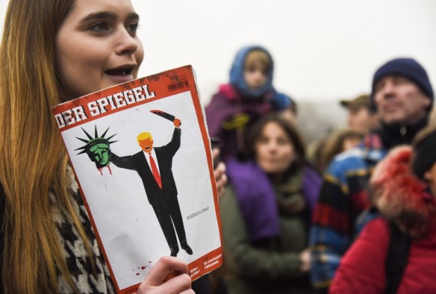 A young woman holds the last edition of "Der Spiegel" magazine with a cover designed by Edel Rodriguez, as she protests against the travel ban imposed by US President Donald Trump, on February 4, 2017, in Berlin. / AFP PHOTO / ODD ANDERSEN