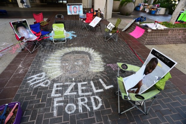 A chalk drawing of Ezell Ford, a mentally ill African-American man who was killed by Los Angeles policetwo years ago, is encircled by photos of other black and brown people also killed by police, at an encampment of activists associated with the Black Lives Matter movement, August 12, 2016, outside of City Hall in Los Angeles, California.     The activists, who have already spent 32 days camped outside City Hall to protest police killings of brown and black men and women, plan to remain in the camp until Los Angeles Police Department Chief Charlie Beck, who activists call the leader of "the most murderous police force in the country" is fired or resigns.  / AFP PHOTO / Robyn BECK