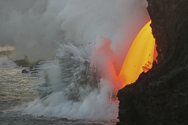 This Jan. 29, 2017 photo provided by the U.S. Geological Survey shows a lava stream pouring out of a tube on the sea cliff at the Kamokuna ocean entry at the Hawaii Volcanoes National Park on the Big Island of Hawaii. A dramatic "firehose" stream of lava is shooting out of a sea cliff on Hawaii Island, splashing into the Pacific Ocean below and exploding upon impact. A USGS geologist with the Hawaii Volcano Observatory said Wednesday, Feb. 1, 2017 that one of the biggest concerns is a large "hot crack" above the lava tube, running parallel to the sea cliff and makes the land susceptible to collapse. (U.S. Geological Survey via AP)