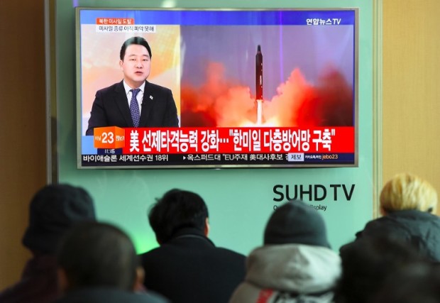 People watch the news showing file footage of North Korea's missile launch at a railway station in Seoul on February 12, 2017. North Korea fired a ballistic missile on February 12 in an apparent provocation to test the response from new US President Donald Trump, the South Korean defence ministry said. / AFP PHOTO / JUNG Yeon-Je