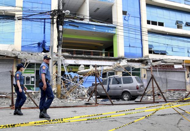 Police officers in front of quake-damaged building in Surigao City - 12 Feb 2017