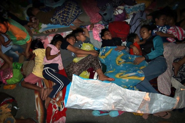 This picture taken on February 11, 2017 shows residents sleeping on the pavement, as they take shelter from strong aftershocks of an earthquake, on the grounds of the Provincial Capitol in Surigao.  Residents of the southern town of Surigao in Mindanao island spent the night huddled in fear as aftershocks rocked the city following the 6.5-magnitude quake which struck late February 10 when many people were already in bed. / AFP PHOTO / ERWIN MASCARINAS