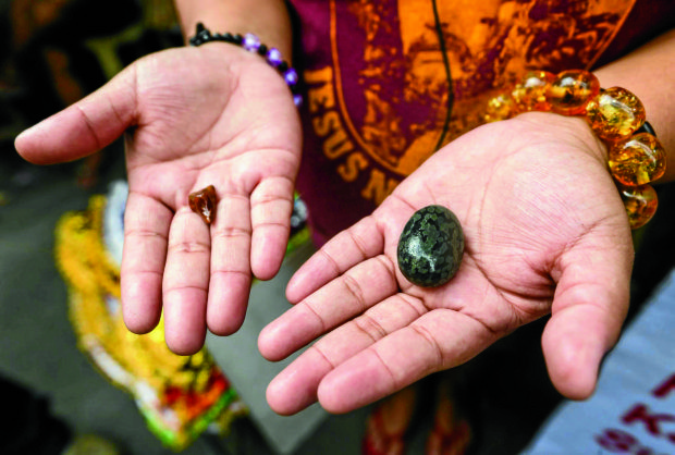 IN DEMAND Street vendor Erica Policarpio shows a “ngipin ng kidlat” (left) believed to protect one from bullets and the “niyog na bato” for supposed invisibility. —LYN RILLON