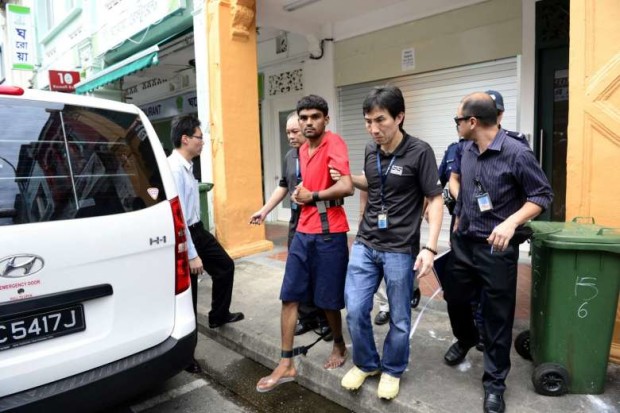 Murder suspect Ramzan Rizwan (in red) being escorted by investigators outside the lodging house at 6 Rowell Road on June 19, 2014. STRAITS TIMES FILE PHOTO