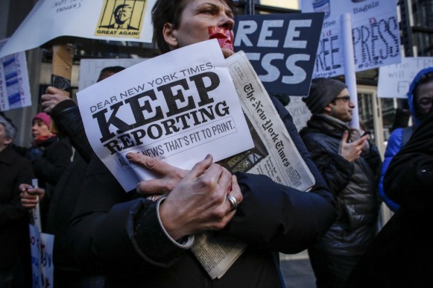 A woman covers her mouth with tape as people take part in a protest outside the New York Times on February 26, 2017 in New York. The White House denied access Frebuary 24. 2017 to an off-camera briefing to several major US media outlets, including CNN and The New York Times. Smaller outlets that have provided favorable coverage however were allowed to attend the briefing by spokesman Sean Spicer. The WHCA said it was "protesting strongly" against the decision to selectively deny media access. The New York Times said the decision was "an unmistakable insult to democratic ideals," CNN called it "an unacceptable development," and The Los Angeles Times warned the incident had "ratcheted up the White House's war on the free press" to a new level.  / AFP PHOTO / KENA BETANCUR