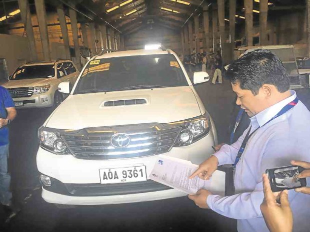Lawyer Randy Escolango, deputy administrator for legal affairs of the Subic Bay Metropolitan Authority, inspects the missing vehicles allegedly involved in a car rental scam. —ALLAN MACATUNO