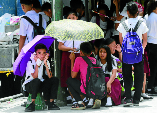 PHOTO: Students use an umbrella to fend off the heat on Wednesday, March 29, 2017. STORY: 42 to 47ºC peak heat index recorded in 15 areas
