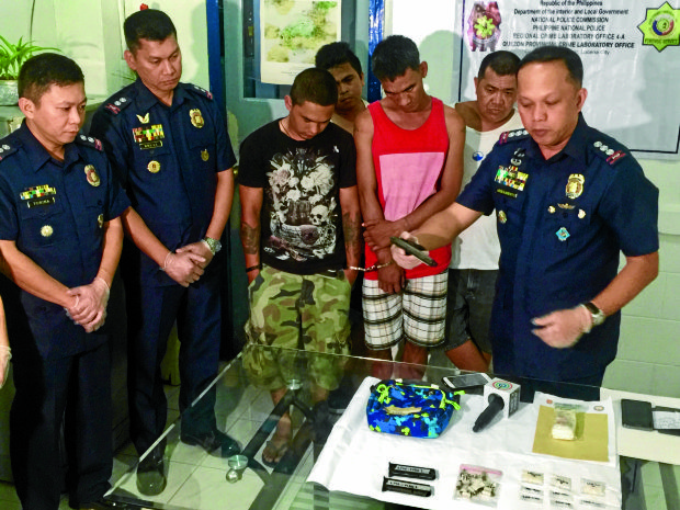 BUSTED  Senior Supt. Rhoderick Armamento (right), Quezon provincial police chief, inspects the guns seized from suspected drug users who have reportedly been recruited by syndicates as pushers. Supt. Arturo Brual (second, from left), Lucena City police chief, says the new pushers fill the void in the drug trafficking network. —CONTRIBUTED PHOTO