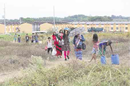 Families belonging to the urban poor group Kadamay pass through a vacant lot on their way to houses they are occupying at the Atlantica housing project in Pandi town, Bulacan province.  —JOAN BONDOC
